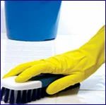 Cleaning hand with yellow glove and scrubbing brush